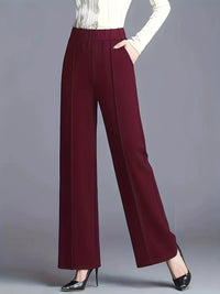 Maroon wide-leg pants worn with a white top on a gray background