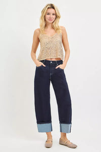 Woman wearing a patterned top and dark blue jeans on a white background