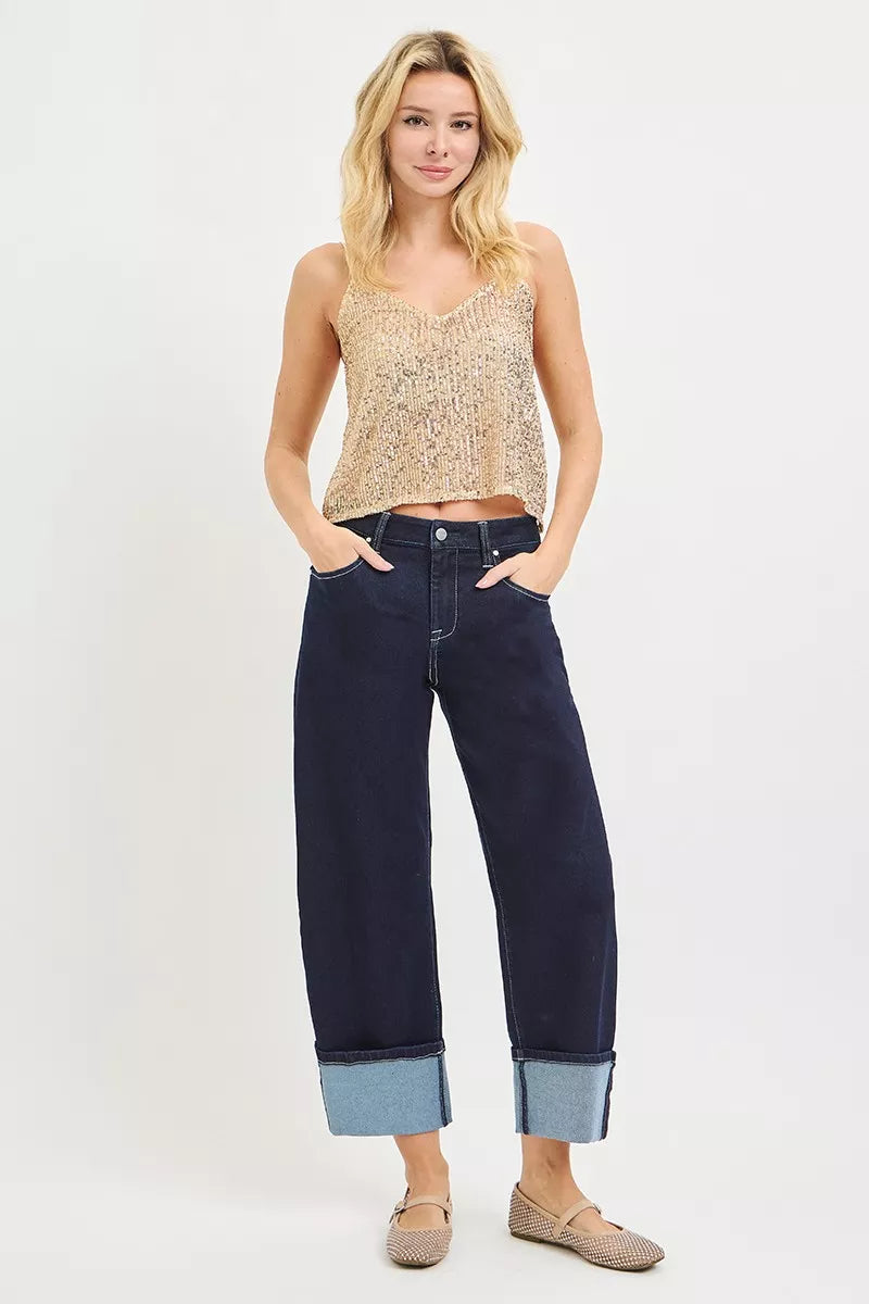 Woman wearing a patterned top and dark blue jeans on a white background
