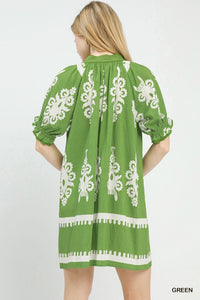 Green dress with white embroidery on a plain background