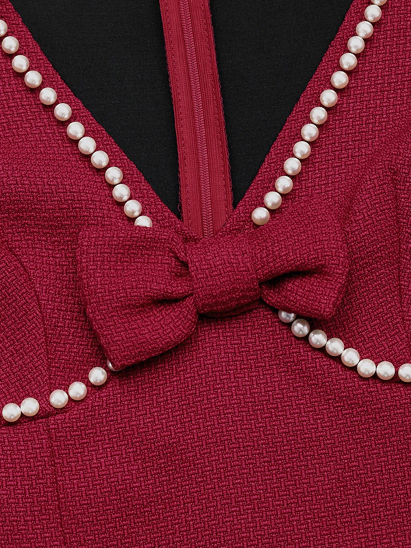 Red garment with a bow and pearl trim on a black background