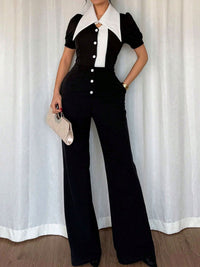 Person wearing a black and white outfit with a white curtain background