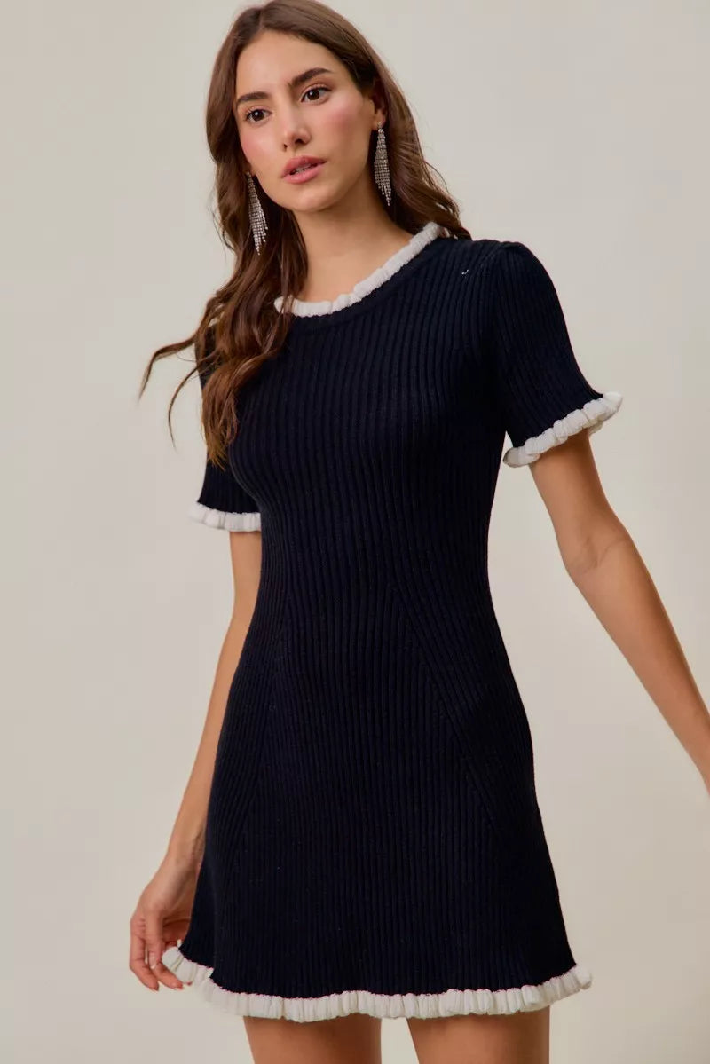 Woman wearing a navy ribbed dress with white trim on a plain background