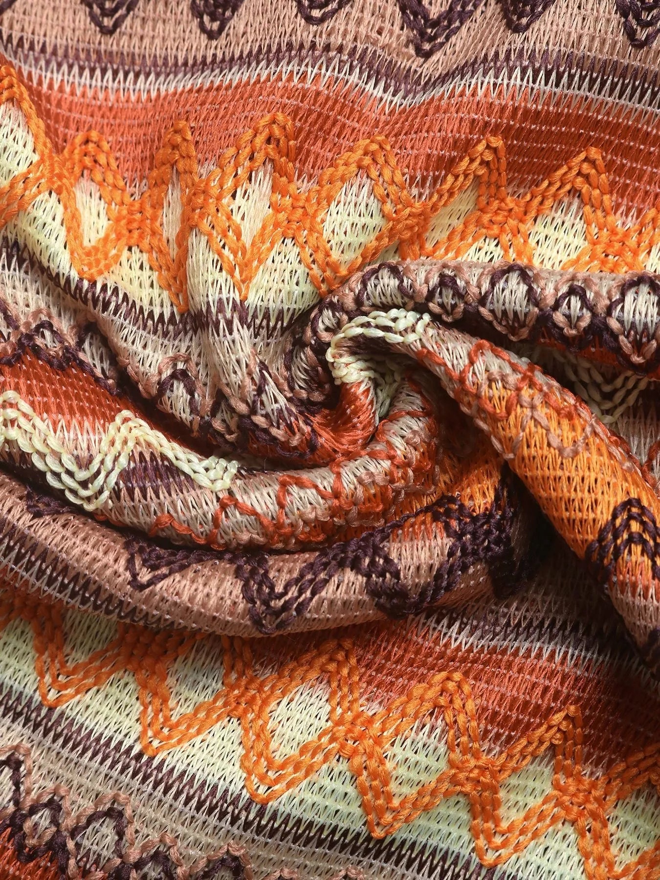Close-up of a patterned fabric with orange, brown, and beige colors.