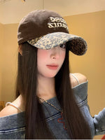 Person wearing a brown cap with leopard print visor against a beige wall.