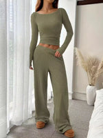 Person wearing a green ribbed knit outfit in a room with white curtains and a vase.