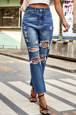 Person wearing ripped blue jeans on a city street.
