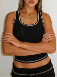Person wearing a black sports bra and leggings with white trim against a plain background