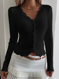 Black long-sleeve top with sheer neckline and white pleated skirt on a plain background