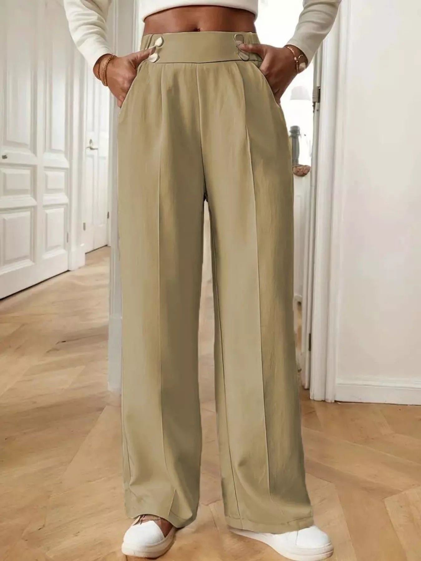 Person wearing beige wide-leg pants in a room with wooden flooring.