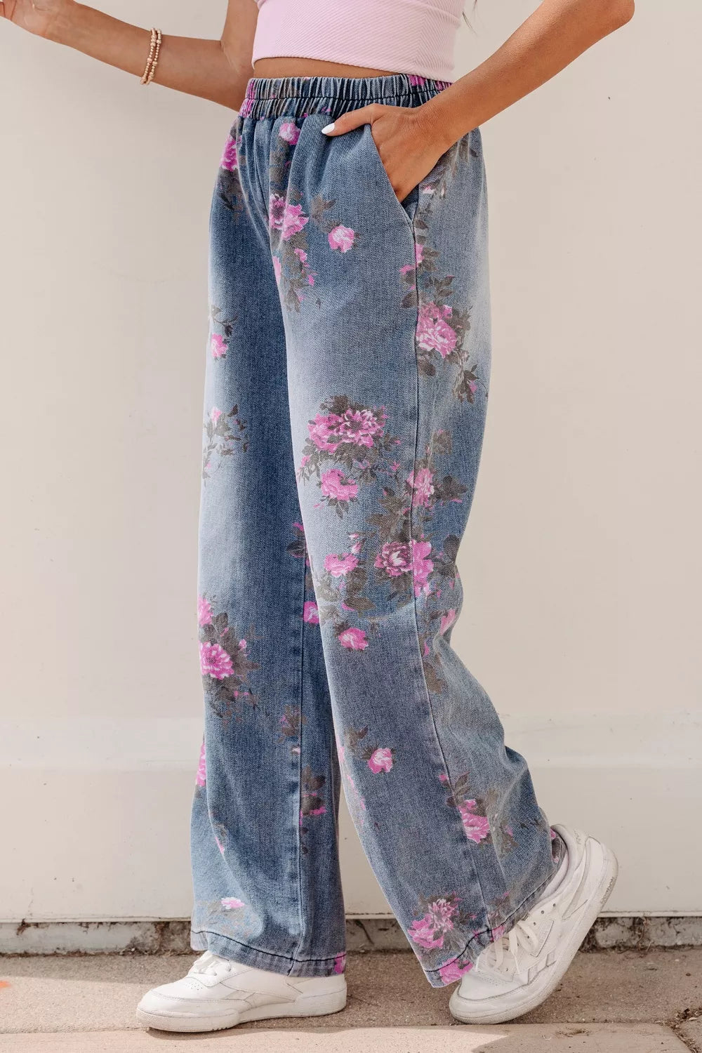 Person wearing floral denim pants with a plain background