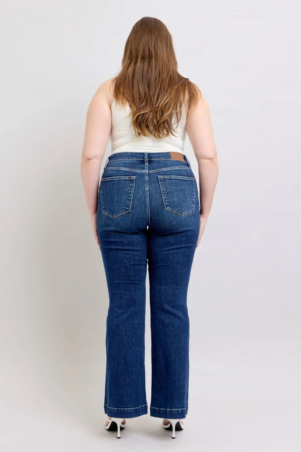 Person wearing blue jeans from behind on a plain background