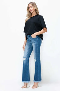 Woman wearing a black top and blue jeans on a white background
