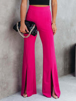 Person wearing bright pink pants with a black clutch against a gray background