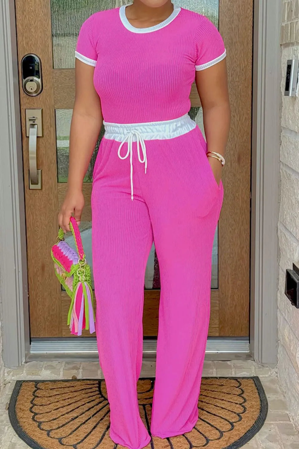 Person wearing a pink outfit standing in front of a door.