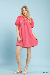 Woman wearing a pink dress with puff sleeves on a light blue background