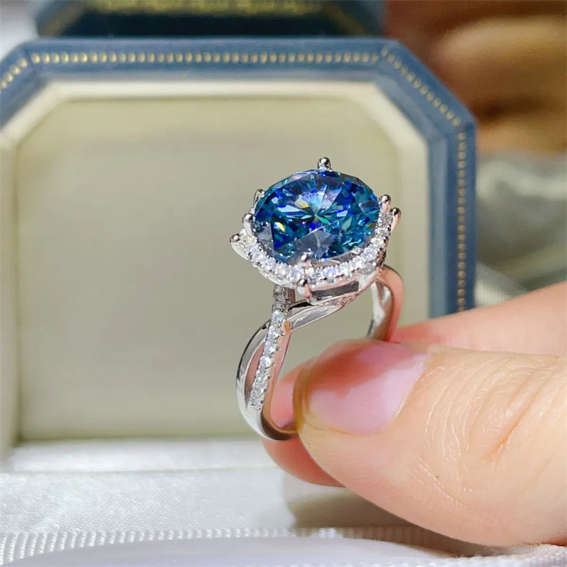 Silver ring with a blue gemstone held by a hand against a blurred background