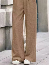 Beige wide-leg pants worn by a person standing on a concrete surface.
