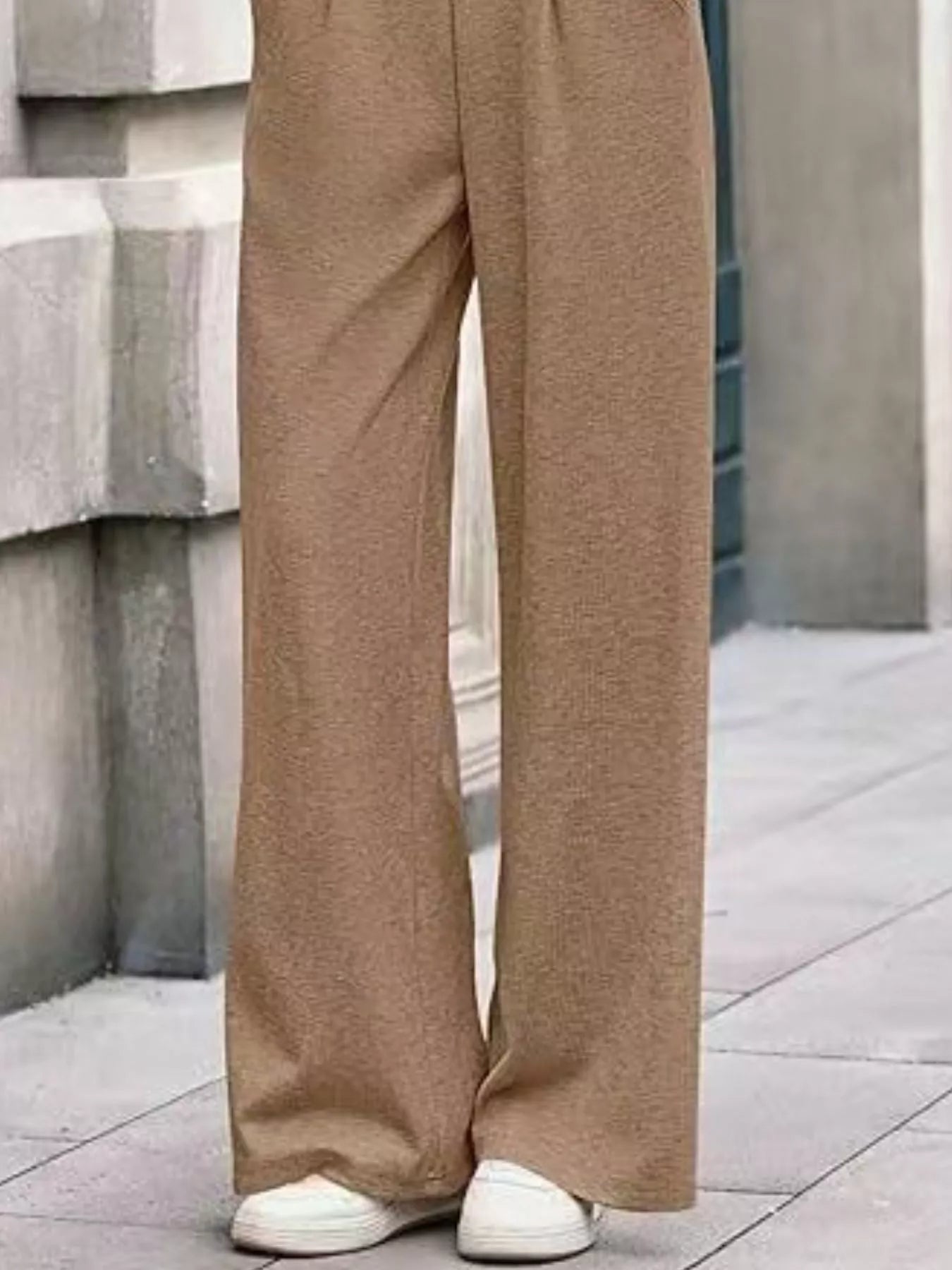 Beige wide-leg pants worn by a person standing on a concrete surface.