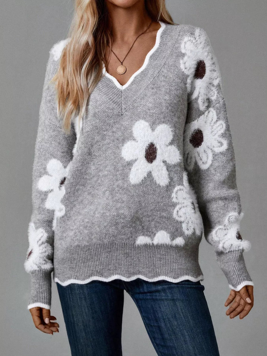 Gray sweater with white floral patterns worn by a person on a gray background