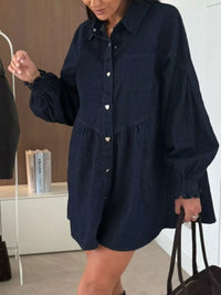Person wearing a navy blue button-up dress in an indoor setting.