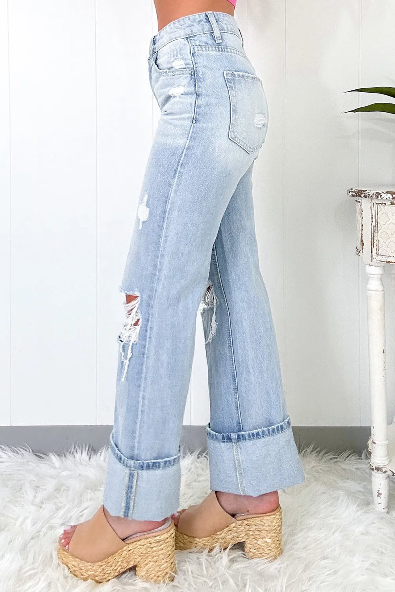 Light blue distressed jeans worn by a person on a white rug.
