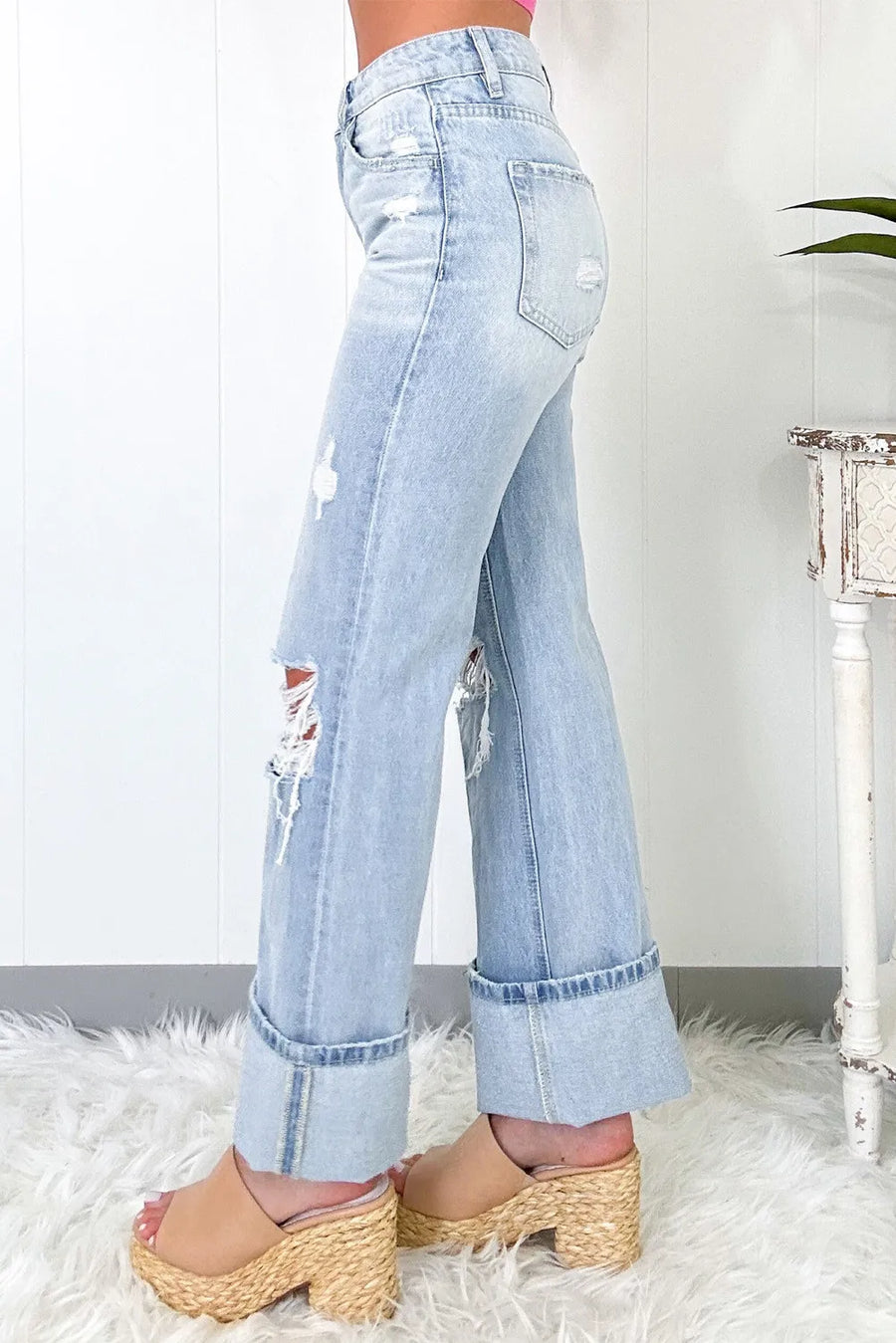 Light blue distressed jeans worn by a person on a white rug.