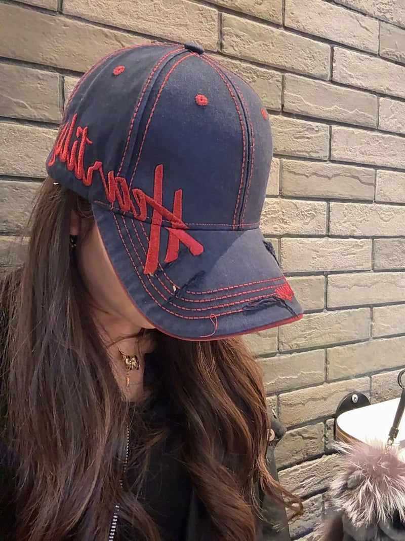 Person wearing a navy blue cap with red text against a brick wall.