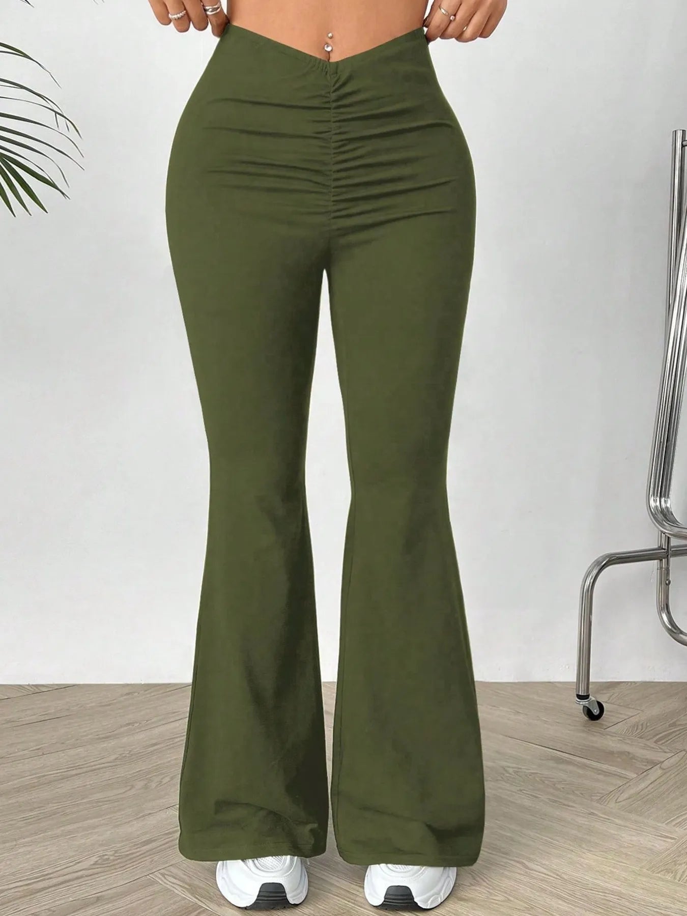 Green flared pants worn by a person on a white background