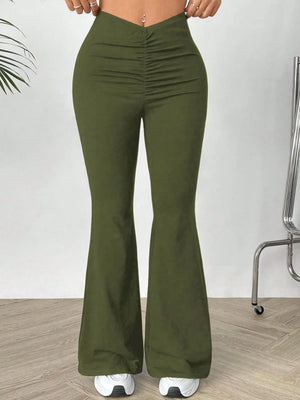 Green flared pants worn by a person on a white background
