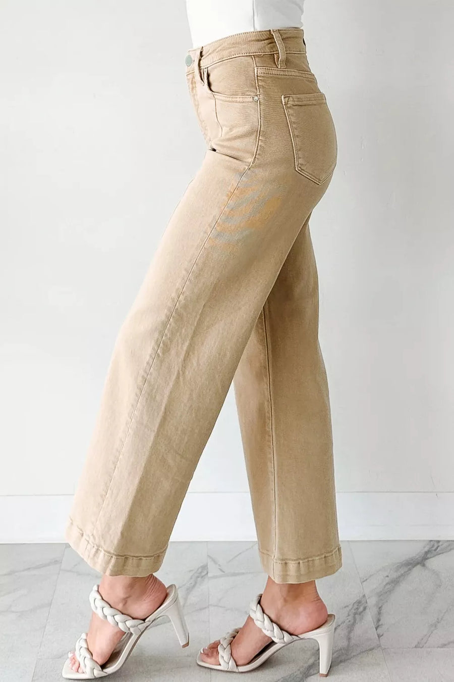 Beige pants worn by a person on a white background