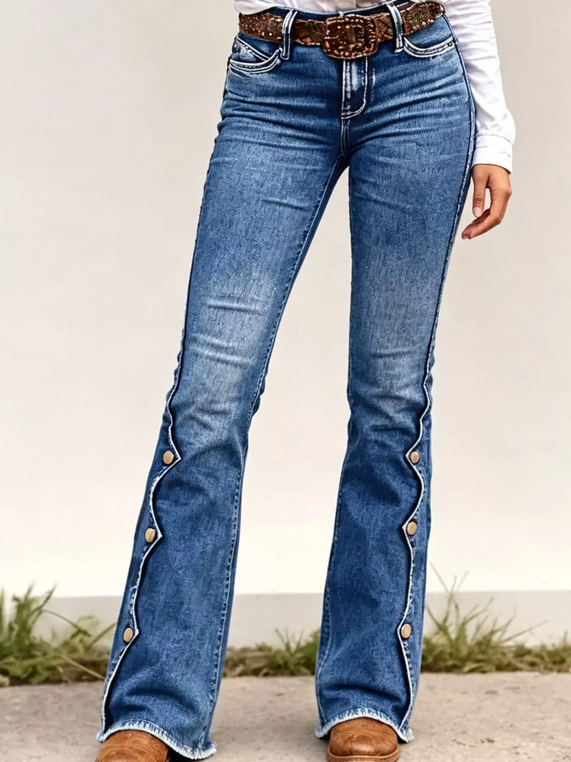 Medium wash blue flare jeans with decorative silver-tone buttons running down the outer sides, styled with a brown belt and white top.