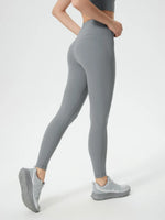 Person wearing gray leggings and matching sneakers on a white background
