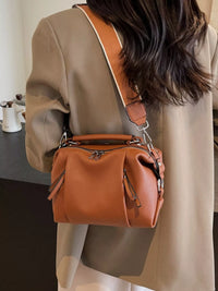 Person wearing a brown leather handbag over one shoulder indoors.