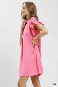 Woman wearing a pink dress with ruffled sleeves on a white background