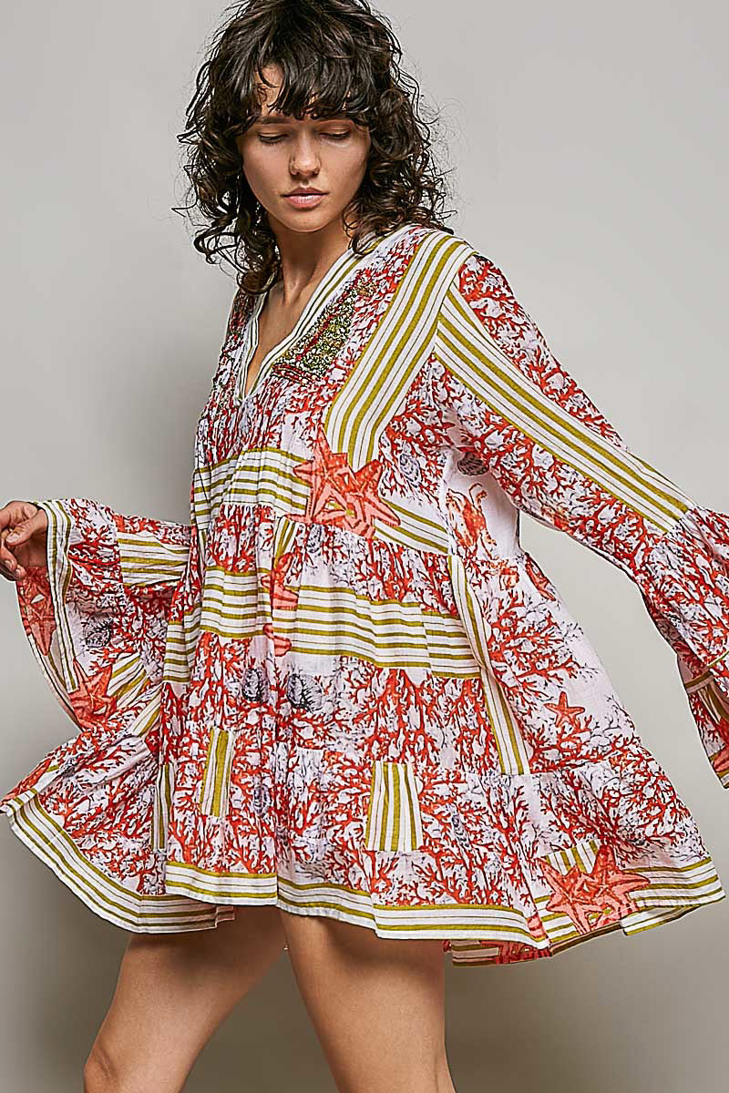 Woman wearing a colorful floral dress with long sleeves against a neutral background