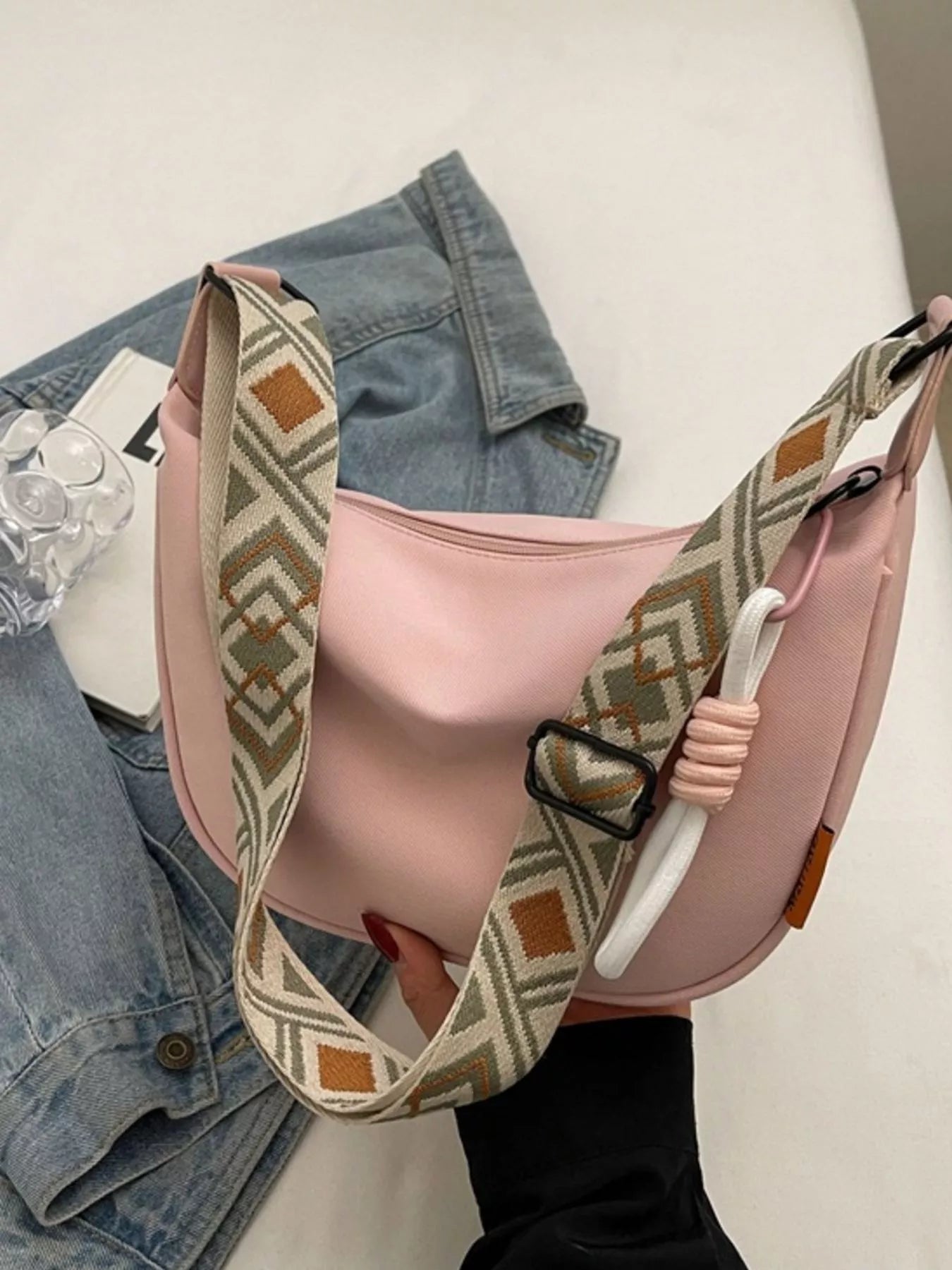 Pink handbag with patterned strap on a white surface