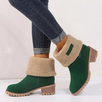 Green ankle boots with beige shearling lining worn with jeans on a white background