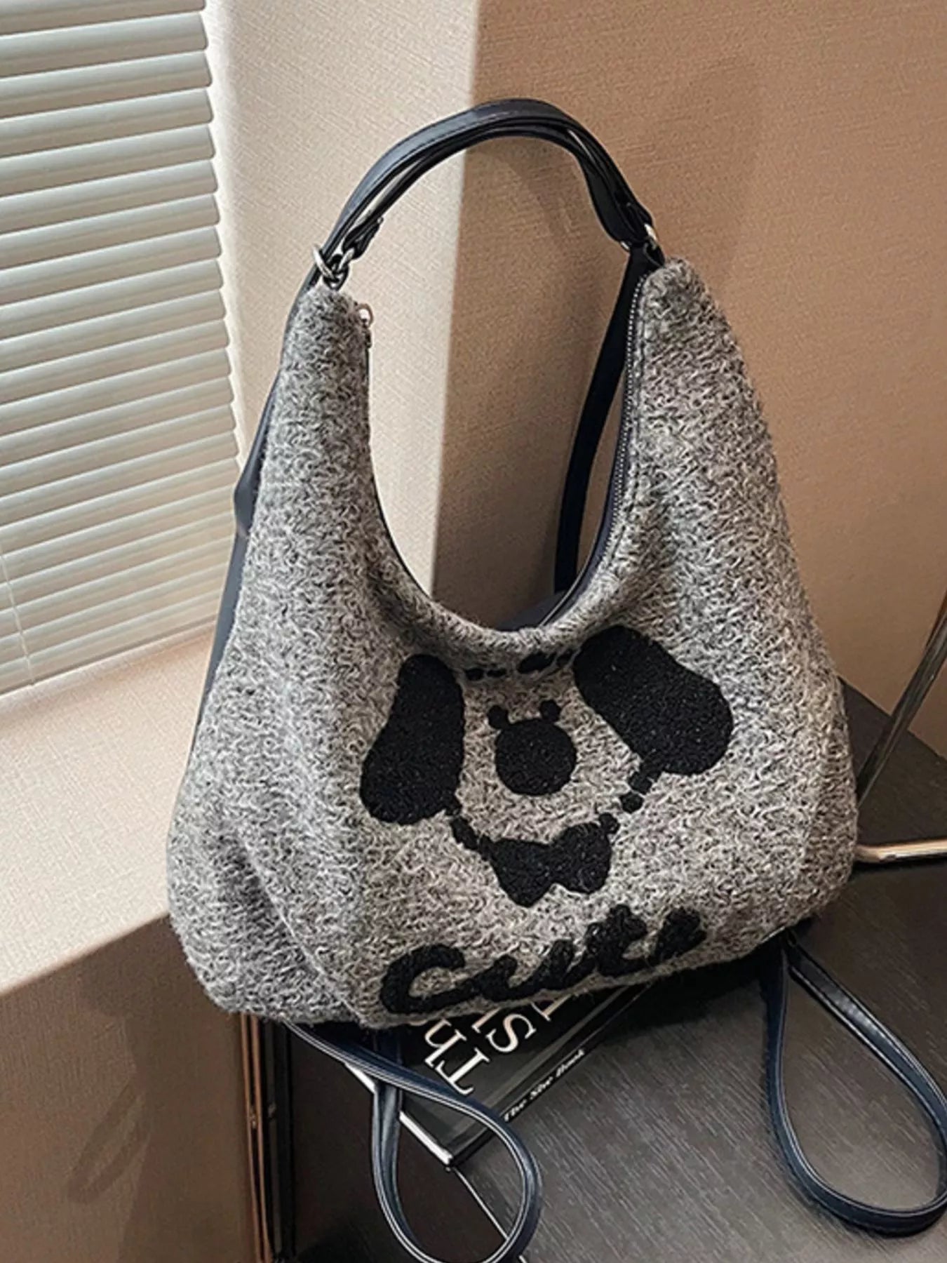 Gray textured handbag with black skull design and 'Cult' branding on a wooden surface.