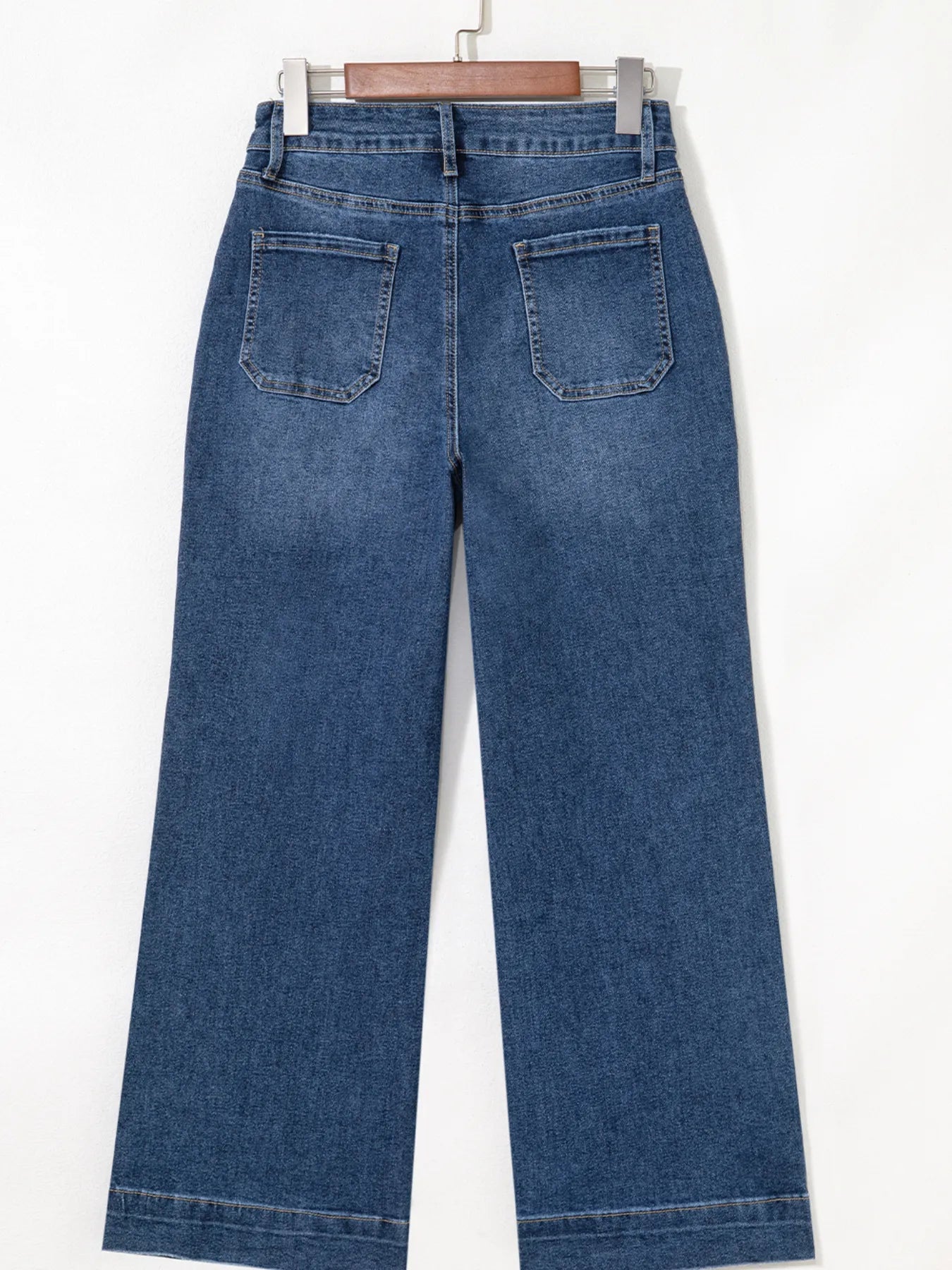 Blue jeans on a hanger against a white background