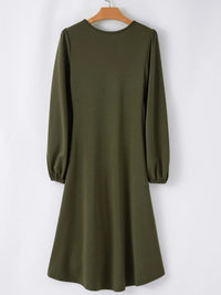 Green dress with long sleeves on a hanger against a white background