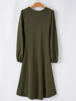 Green dress with long sleeves on a hanger against a white background