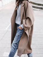 Person wearing a long brown coat over a light blue sweater and jeans.