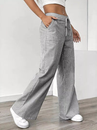 Person wearing gray and white striped wide-leg pants against a plain background