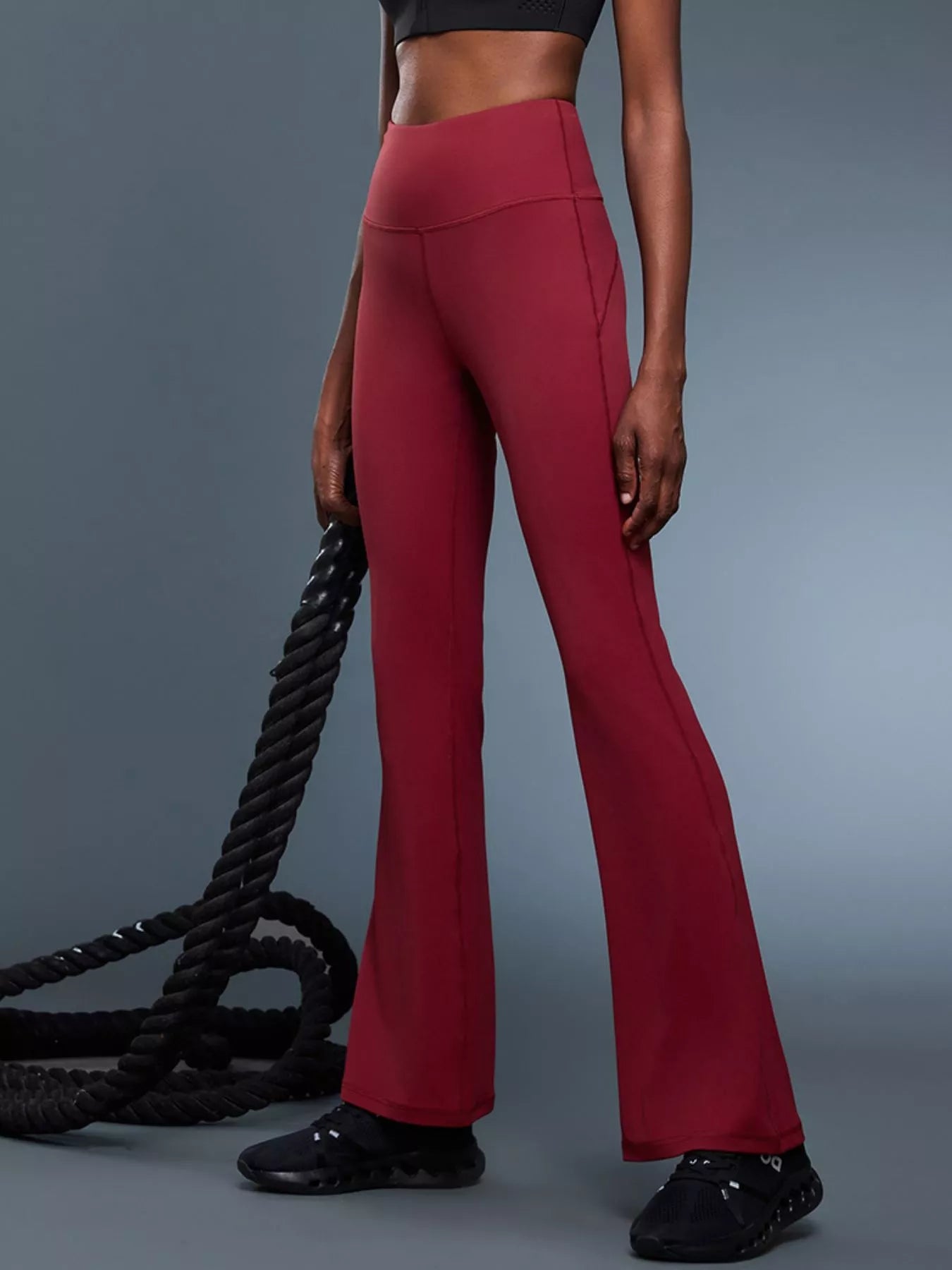 Person wearing red flared pants and black shoes on a gray background