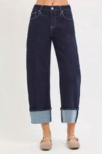 Dark blue jeans with rolled-up cuffs on a white background