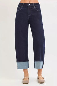 Dark blue jeans with rolled-up cuffs on a white background