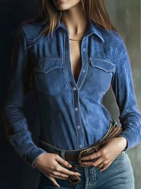 Person wearing a blue denim shirt with a deep neckline against a dark background