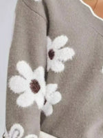 Gray sweater with white floral patterns on a plain background