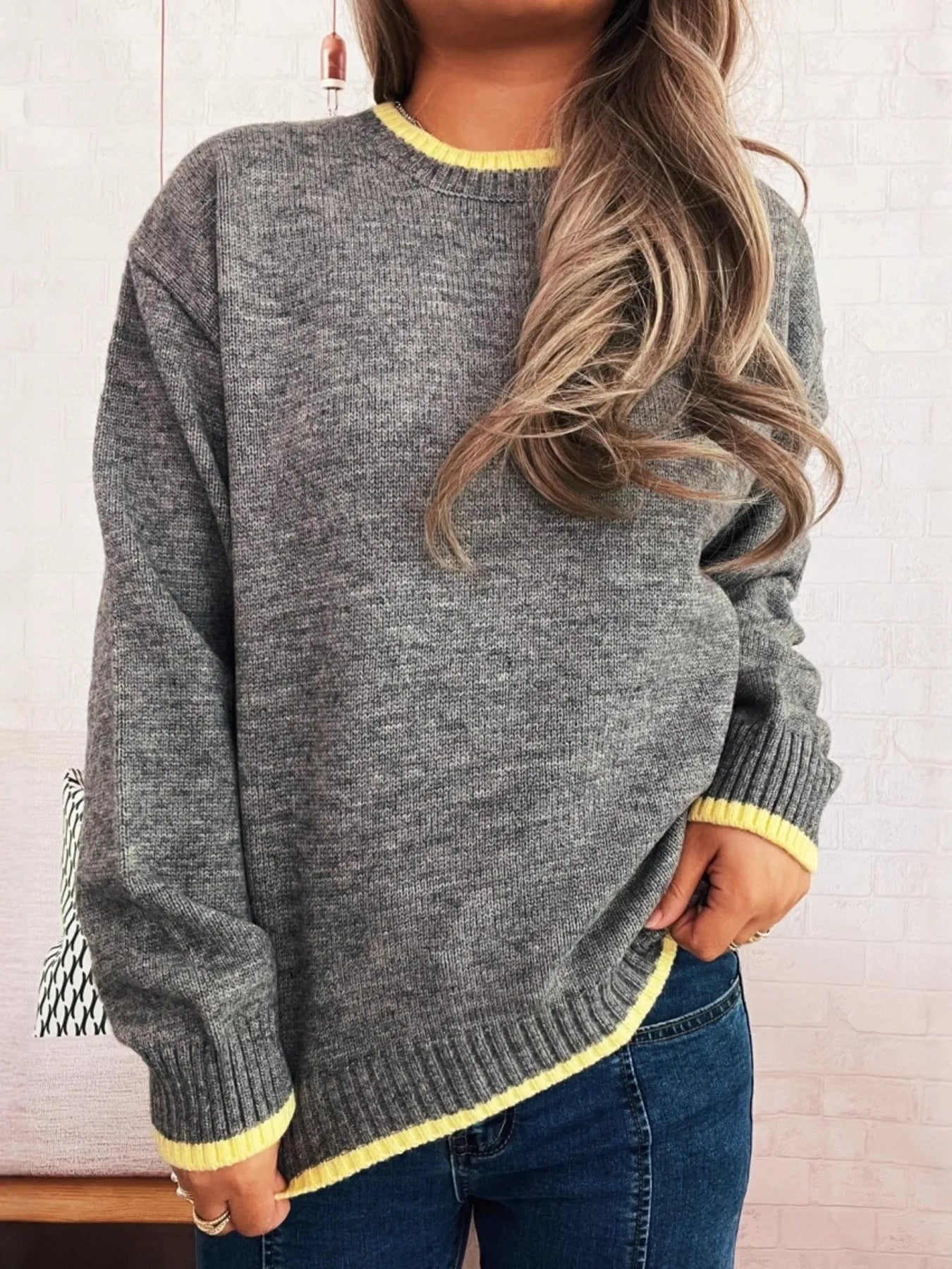Person wearing a gray sweater with yellow trim against a white background